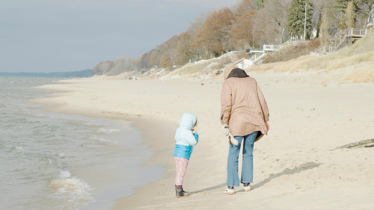 Woman and child walk on a sandy beach